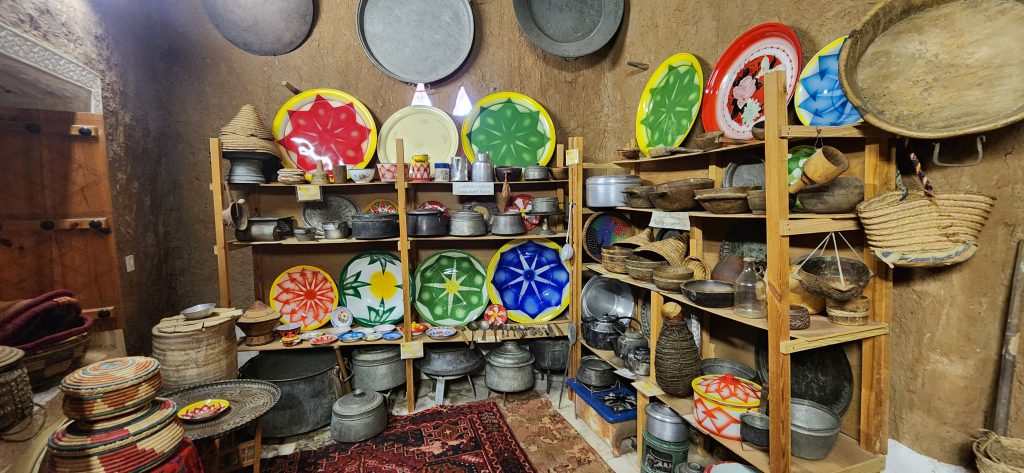 Colorful enamelware and vintage utensils displayed on wooden shelves, showcasing Saudi Arabia's domestic heritage and traditional craftsmanship.