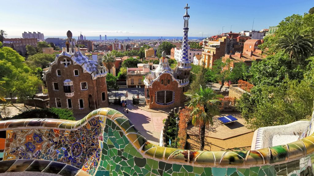 Barcelona's Park G&uuml;ell featuring colorful mosaic architecture, panoramic city view, and lush greenery, highlighting unique travel experiences.