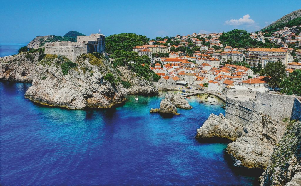 Coastal view of Dubrovnik, Croatia, featuring historic architecture, rocky coastline, and vibrant blue waters, highlighting an off-the-beaten-path travel destination.